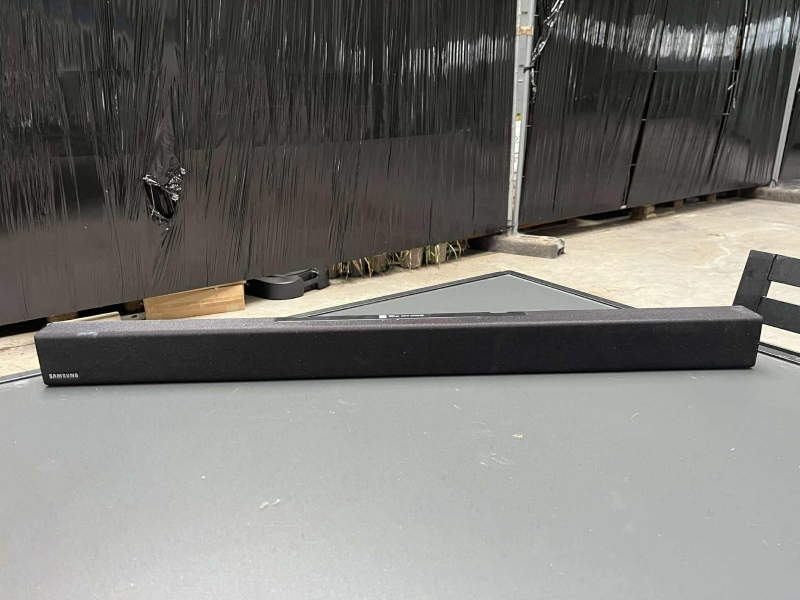une barre de son noire (pas de câble), avec un baffle noir (avec câble) de marque SAMSUNG

