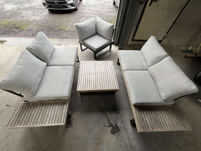 un salon de jardin avec trois fauteuils (un, une place et deux, deux places) et une table basse (76cm x 76cm, hauteur : 32cm), en bois clair et structure métallique gris, avec des coussins gris, à nettoyer 

